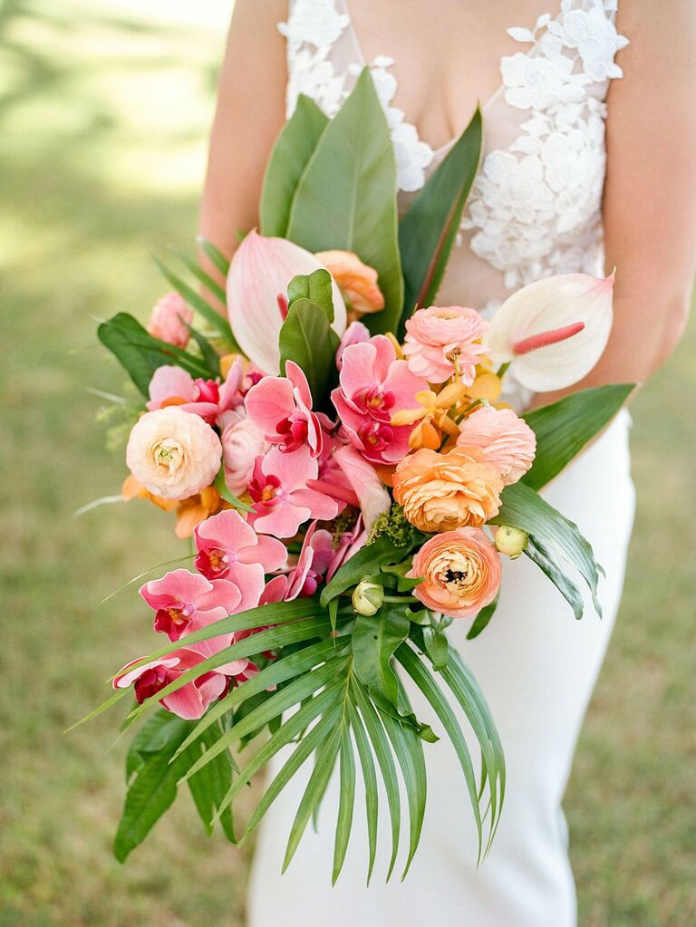 Bride holding tropical wedding flowers with orchid, anthurium and ranuculus