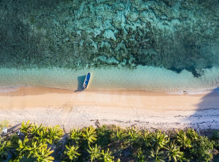 Top down view of an idyllic island with a boat and coral reef in Fiji 