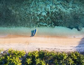 Top down view of an idyllic island with a boat and coral reef in Fiji 