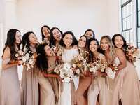 bride laughs with bridesmaids wearing neutral and blush bridesmaid dresses