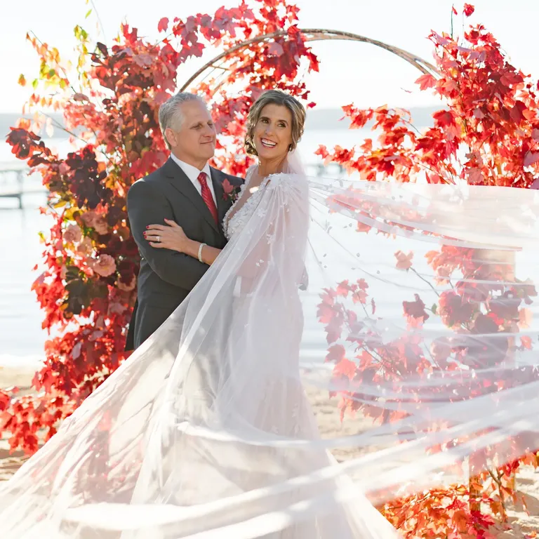 Bride and groom standing at altar of autumn leaves