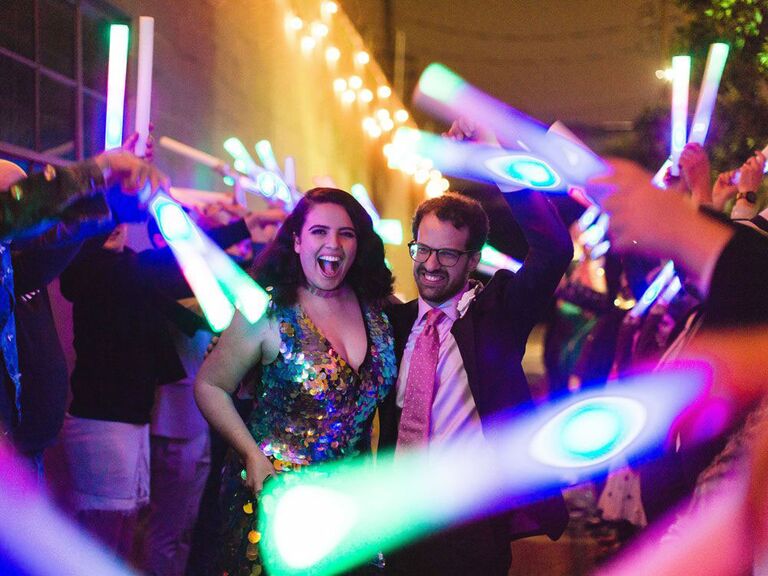 Bride and groom waving light sabers at '90s-inspired wedding