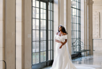 bride poses in off-the-shoulder wedding gown and cape