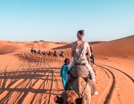 Person riding a camel in Sahara Desert Morocco during a camel expedition