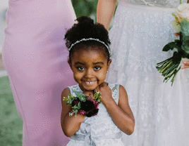 Flower girl smiling in her white flower girl outfit.