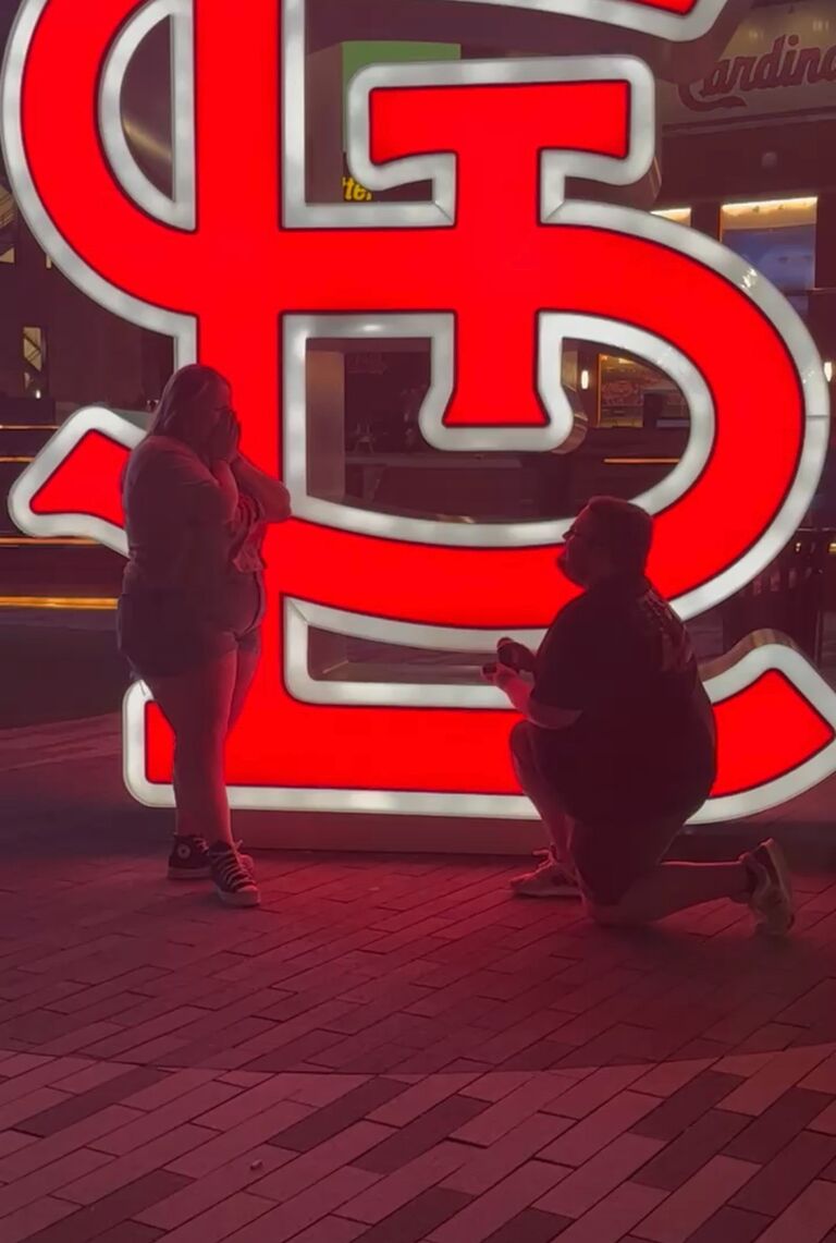 Mason proposed in St. Louis! The entire trip Mason kept telling everyone how much he wanted to get a picture in front the STL sign. Jenna thought it was odd that he was so concerned about a picture, but went to take it if it made him happy. Jenna thought "why is he getting so close to me?" and Mason jokingly (or so Jenna thought) said "Wouldn't this be a cute place for a proposal?" Jenna in disbelief said "no." Mason got down on one knee and of course Jenna said yes! Jenna also learned that Mason had been keeping the ring in their apartment since February while she remained completely oblivious. Mason said this day seemed like the perfect day to propose since everything was going their way. Jenna lost, then found, her ID in Busch Stadium, Fletcher got to announce the 4th inning lineup, and they picked out and named their puppy. 