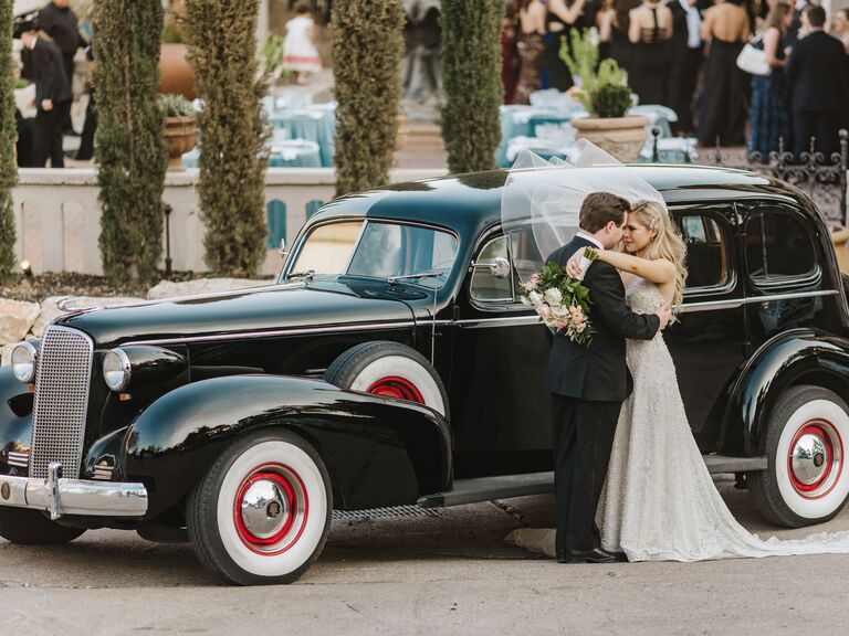 Couple posing for a picture outside a wedding car