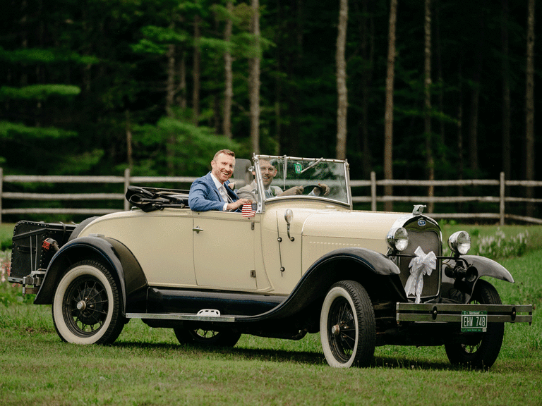 Grooms smiling in vintage car