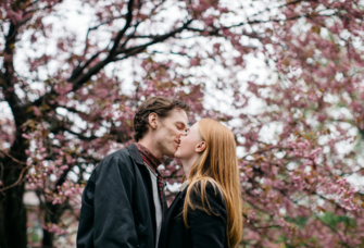 Couple kissing under cherry blossom trees