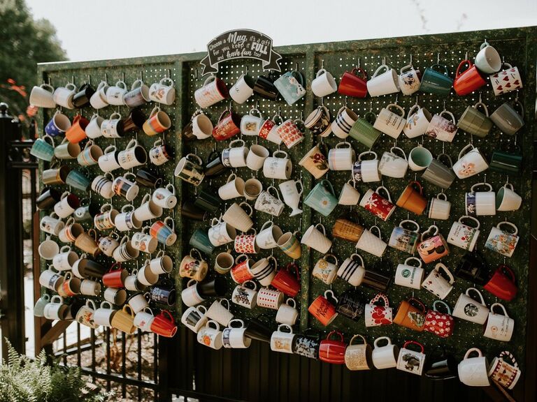 wedding favor display with vintage coffee mugs hanging on pegboard wall