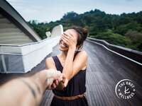 smiling woman holding man's hand and covering her eyes with her hand