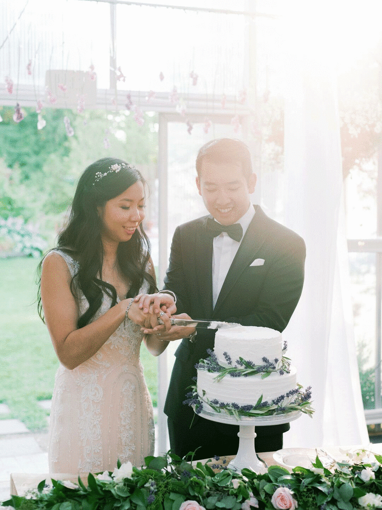 Couple cutting into wedding cake with lavender