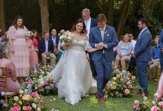 A bride and groom walk hand and hand down the aisle in their wedding recessional