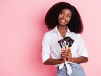 Woman holding makeup brushes in front of pink background