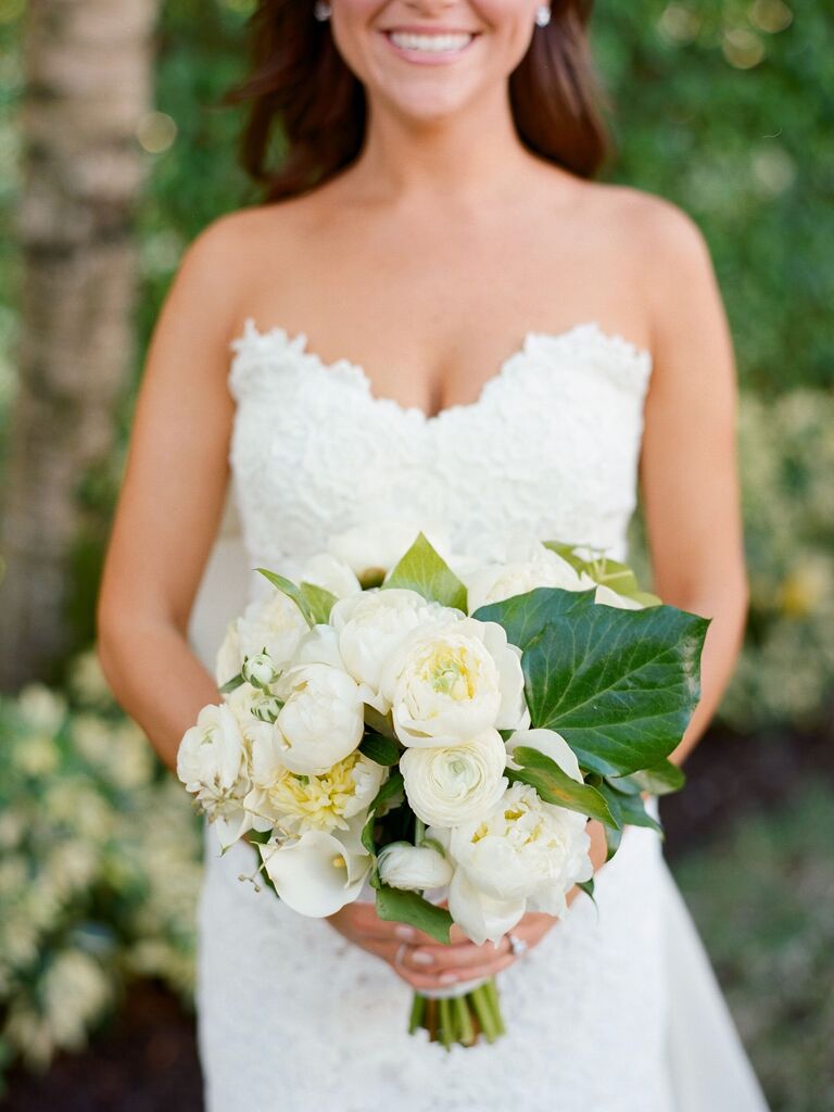 A bride holds a stunning bouquet of lilies and white peonies.