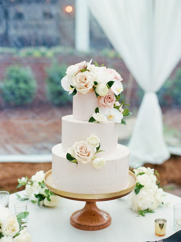 elegant three tier spring wedding cake decorated with pale pink buttercream, ivory flowers and pink roses