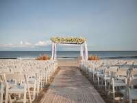 beach wedding ceremony in the hamptons with boho kilim rugs as aisle runner and flower arch at the altar