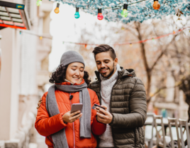 Couple on phones while talking walk outside during the winter