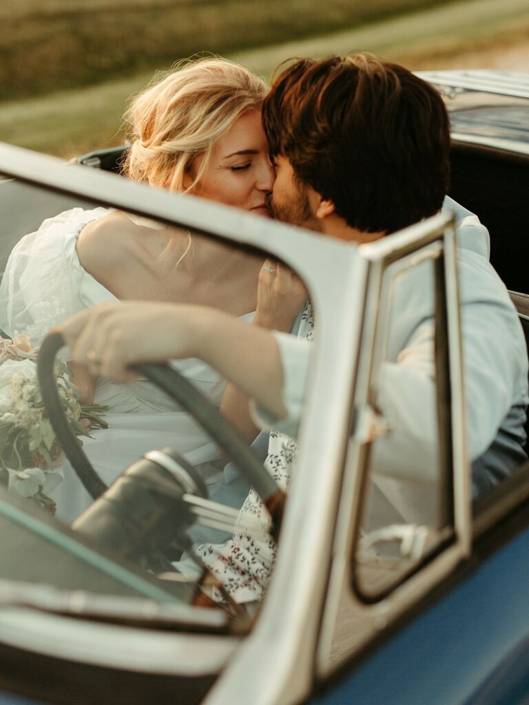 Couple shares a sweet kiss in a retro car. 