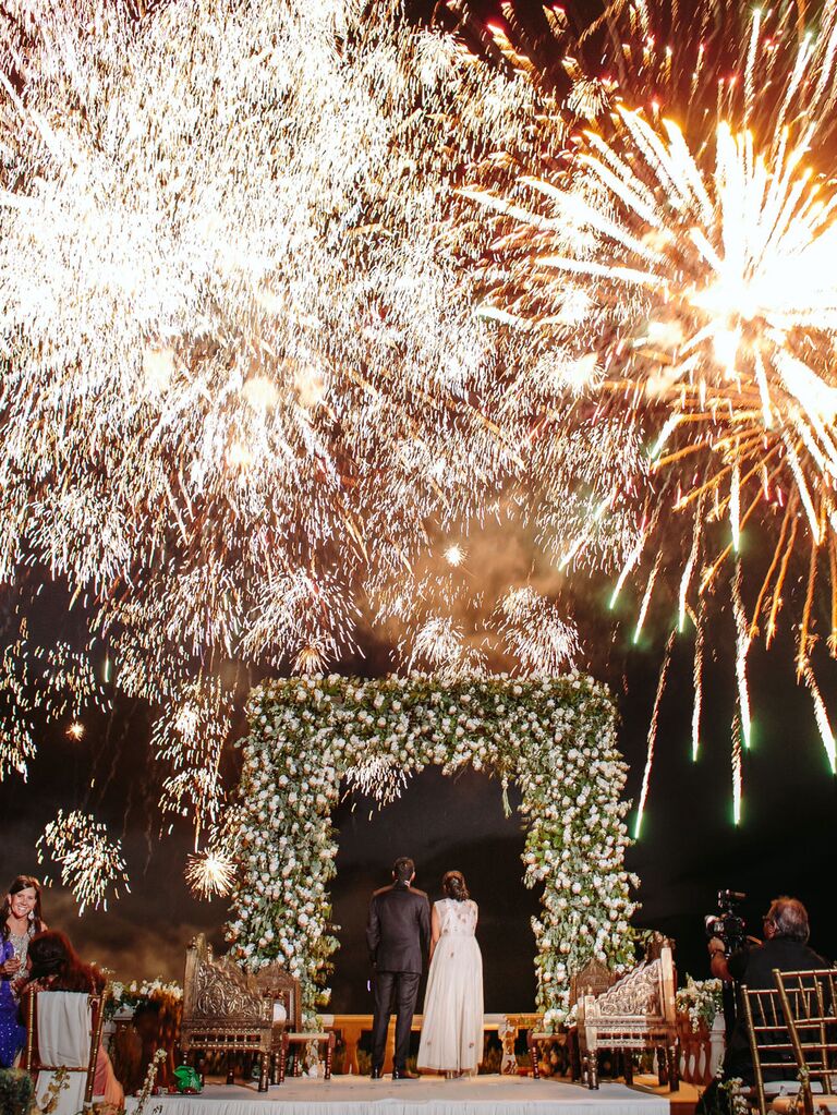 Bride and groom watching fireworks display at wedding reception