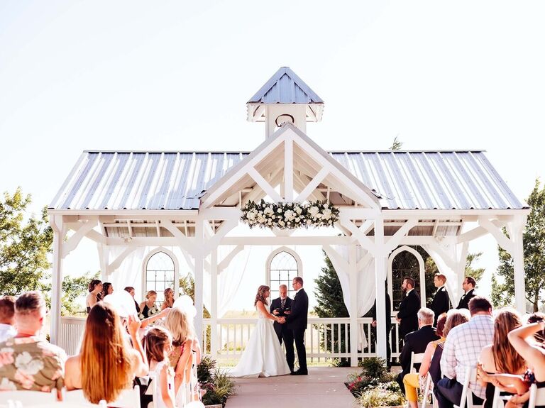Couple exchanging their vows underneath an open air shelter