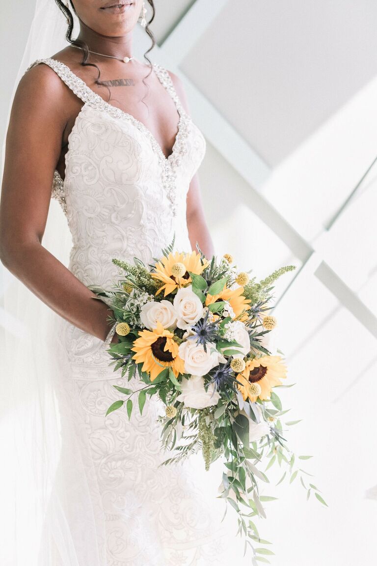 Bride holding rustic cascading sunflower bouquet