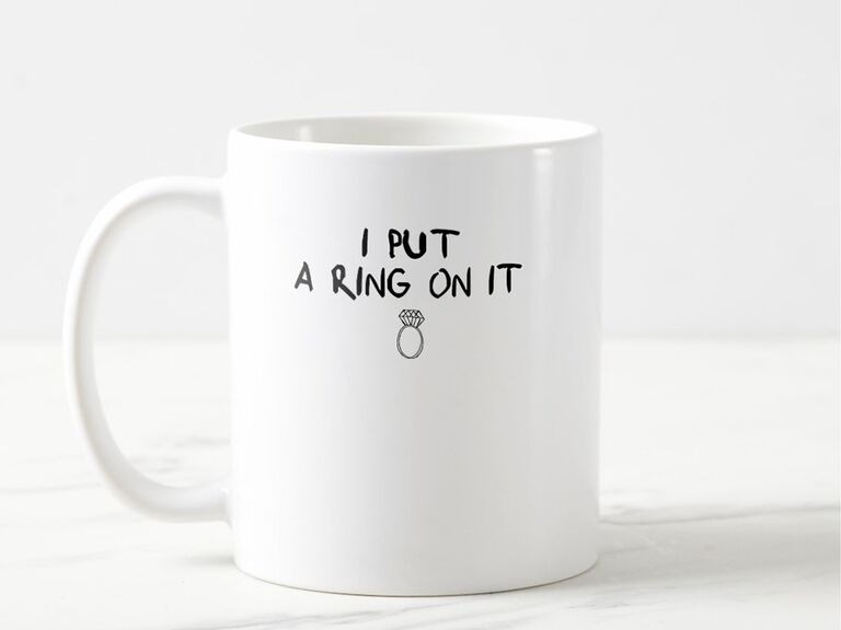 'I put a ring on it' in handwritten black type and small ring graphic on white mug