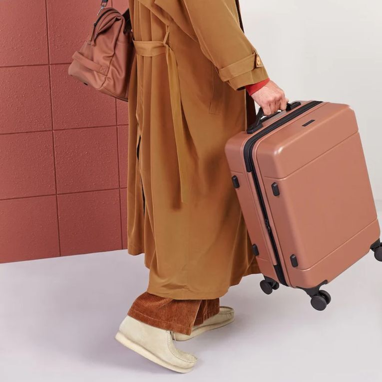 Woman holding a stylish carry on suitcase from CALPAK