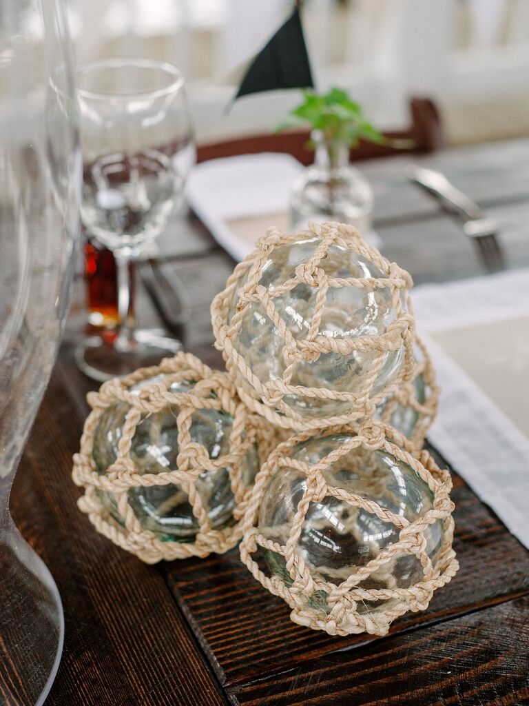 stack of glass balls wrapped in nautical rope decorating wedding tablescape 
