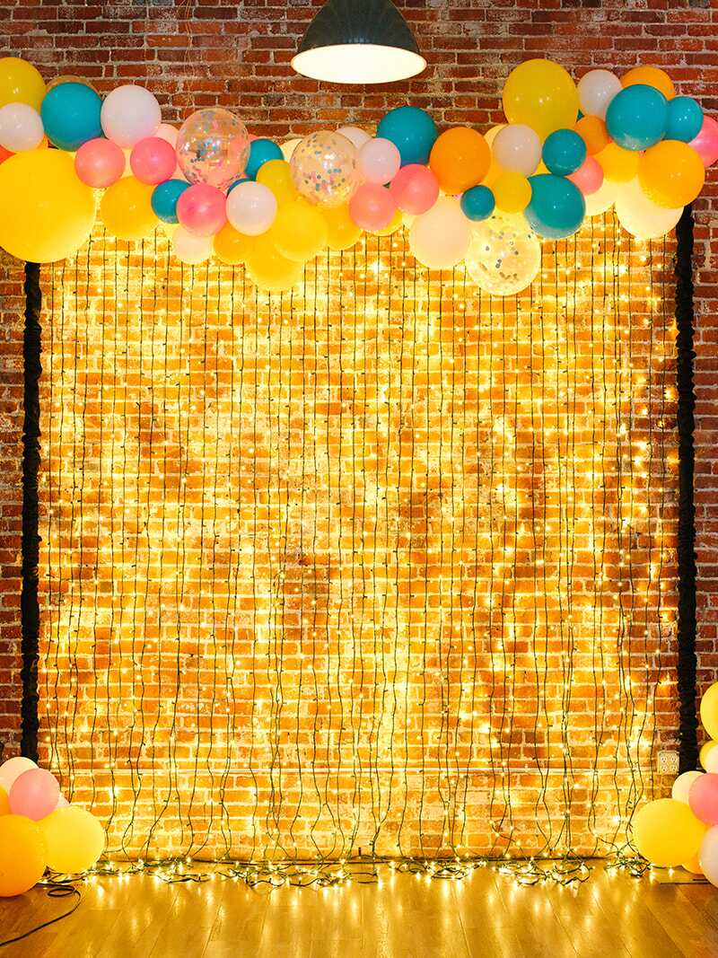 Teal and yellow balloon garland decorating a photo backdrop of string lights