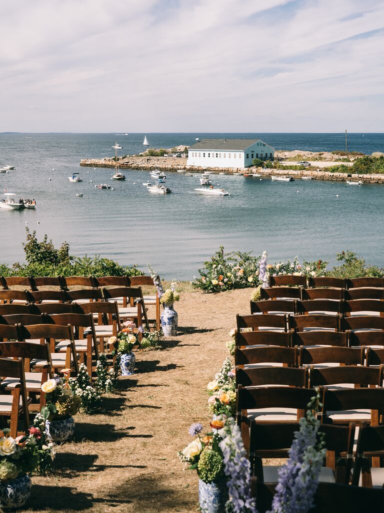 waterfront wedding ceremony with wooden folding chairs and blue chinoiserie vase aisle markers with colorful flowers