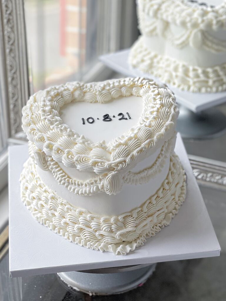 simple heart shaped wedding cake with white icing and wedding date written in black letters