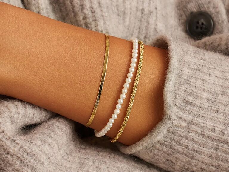 a delicate pearl bracelet worn with two gold bracelets from Gorjana