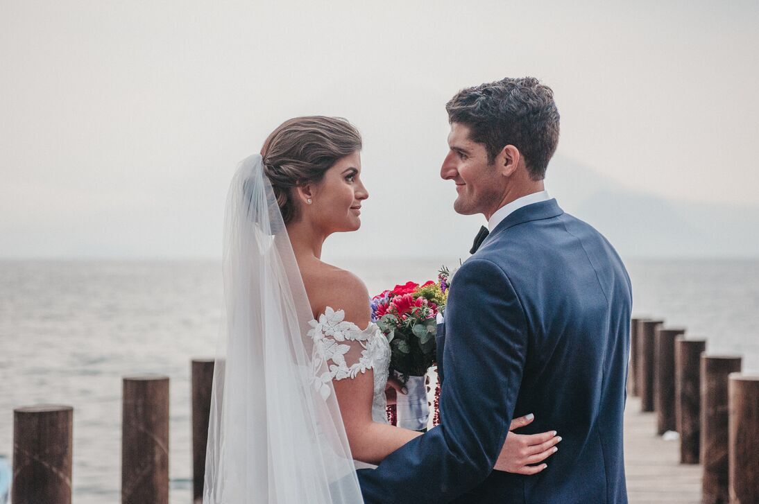A couple look lovingly into each other's eyes by the water
