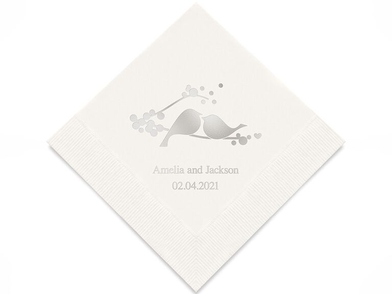 White napkin with birds on a branch graphic, names and date in silver foil type