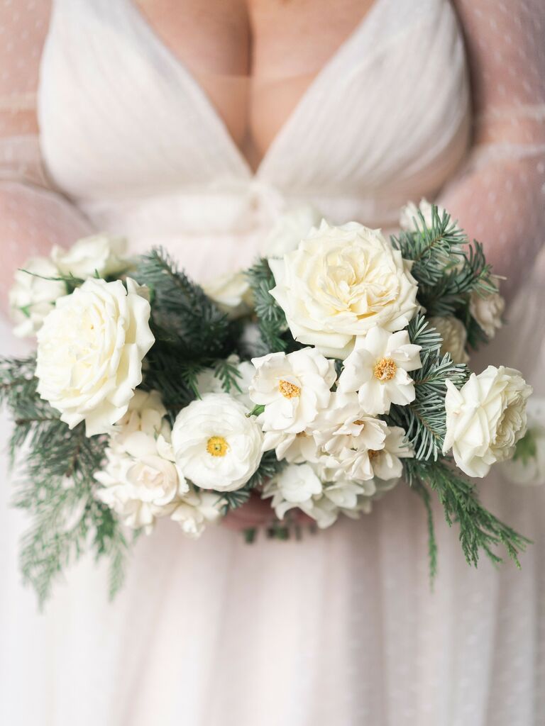This petite white wedding bouquet is perfect for a winter wedding, with shades of dusky green and bright bursts of yellow.