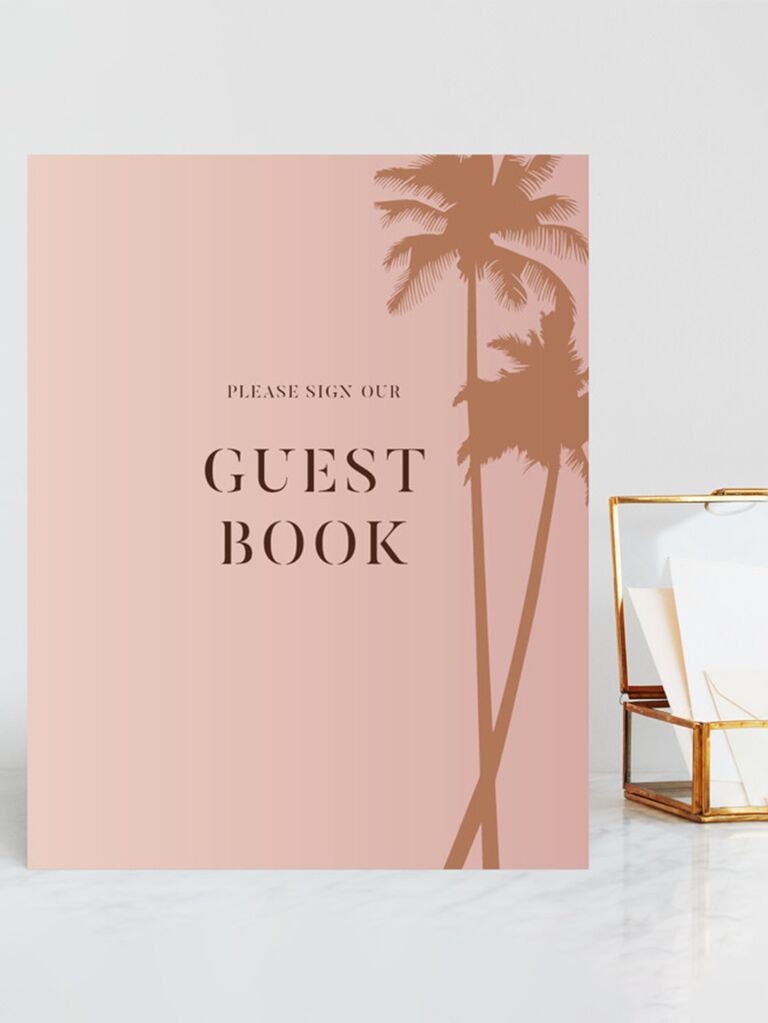 'Please sign our guest book' in minimalist type with gold palm tree graphics on right side on pink sign
