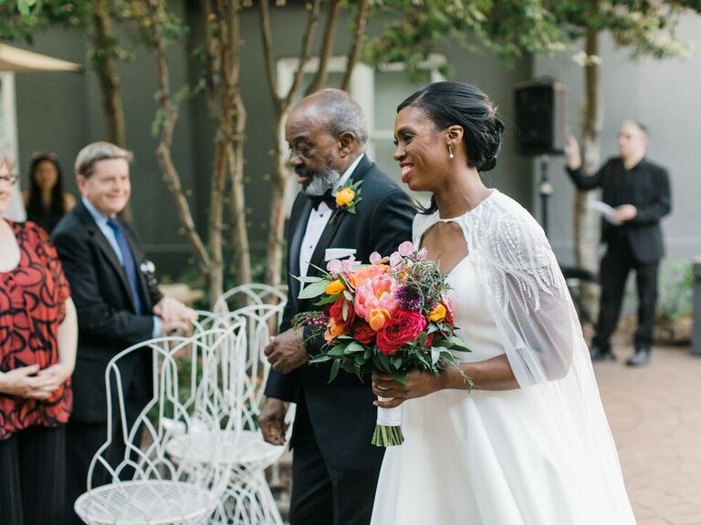 A bride walks down the aisle with her dad.