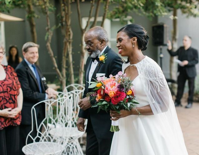 A bride walks down the aisle with her dad.