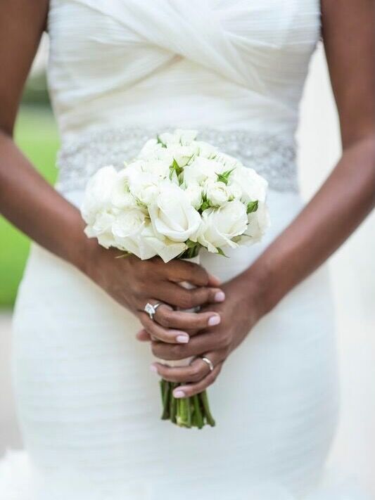 A bride holds a petite white wedding bouquet.