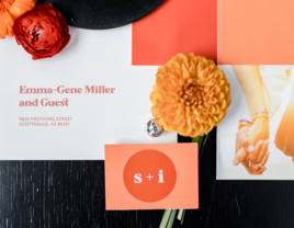 Bright terracotta and salmon themed wedding invitations surrounded by flowers