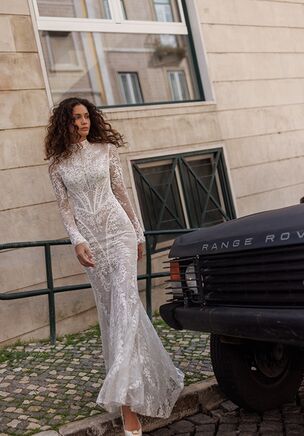 A mermaid silhouette gown, elegantly adorned with lace and intricately hand-embroidered pearls. This exquisite dress features long sleeves, an open back and a luxurious oversized bow that adds a touch of drama and sophistication. The waistband fastens securely, while the bow is easily attachable at the back. The top of the dress is finished with a row of buttons, adding a classic and refined touch. The bow also doubles as a graceful, detachable train, enhancing the gown’s overall elegance and movement.