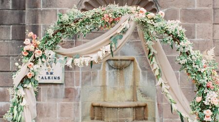 Greenery hanging in the tent at Green Acres with chandeliers and tall  flower centerpieces - Floral V Designs