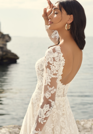 bride standing on the waterfront in long-sleeve lace gown