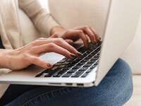 Woman typing wedding website welcome message on laptop