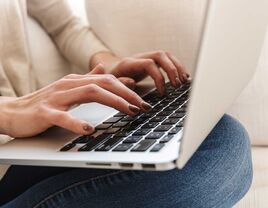 Woman typing wedding website welcome message on laptop