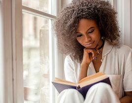 Woman sitting by window reading