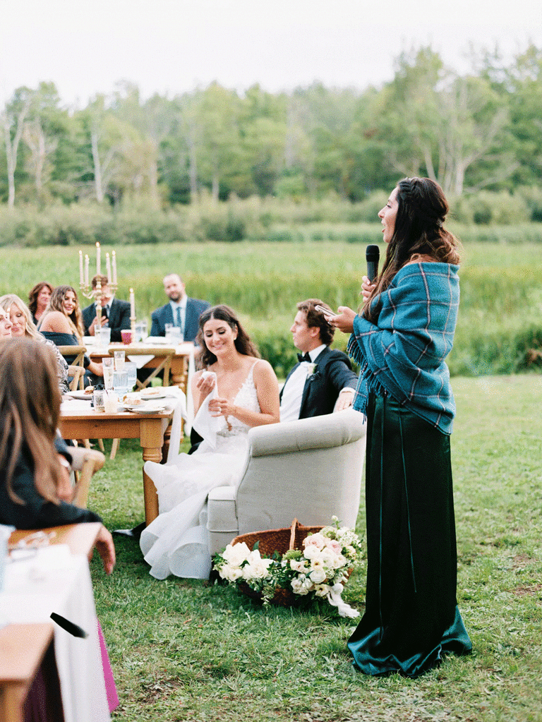 Maid of honor giving wedding speech outdoors