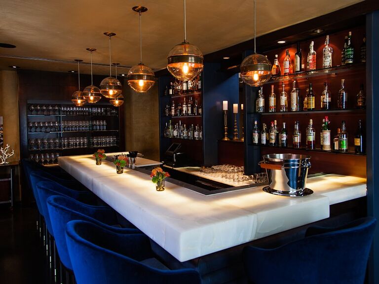 Sleek bar with globe-shaped lights and high back chairs. 