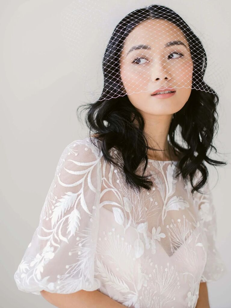 Model wears an elegant birdcage veil. 